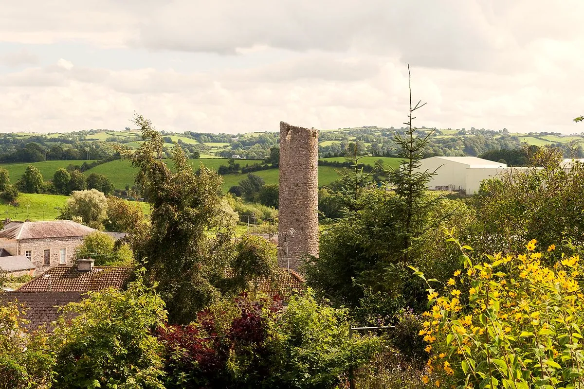Clones round tower among trees and summer flowers